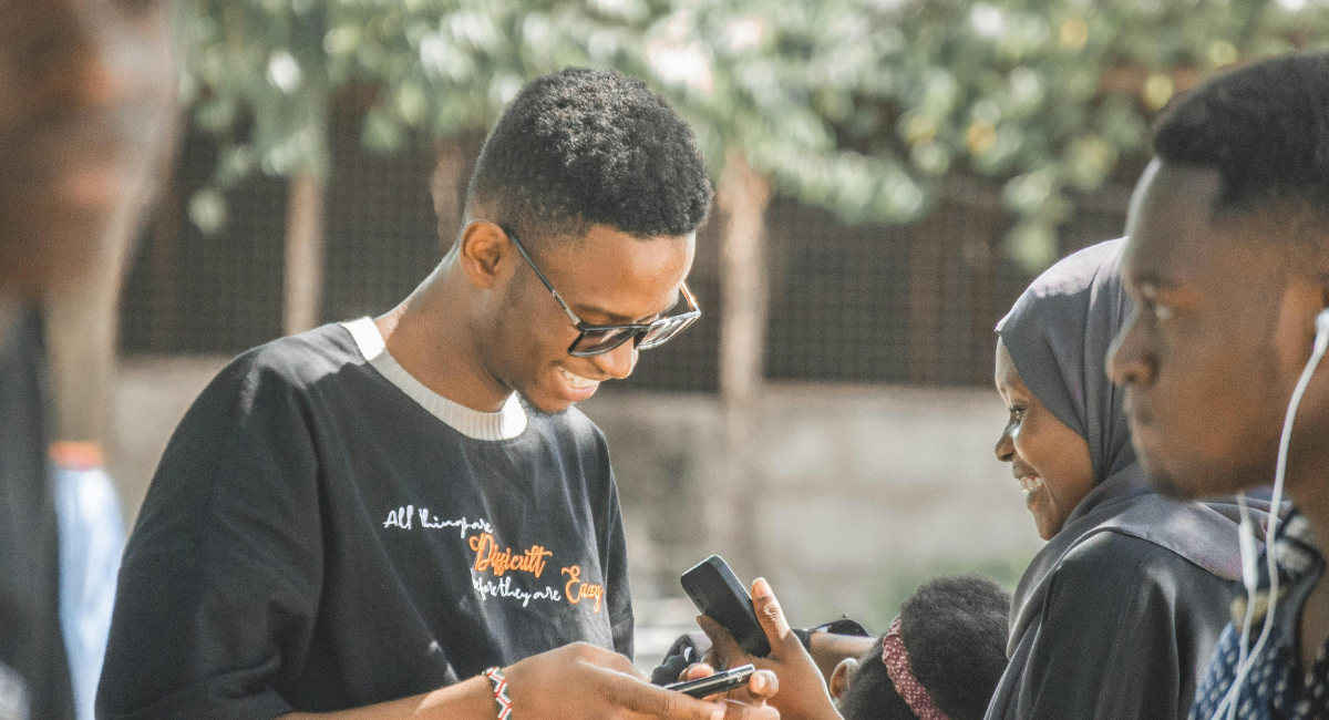Three young Africans, two males and a female on their phones
